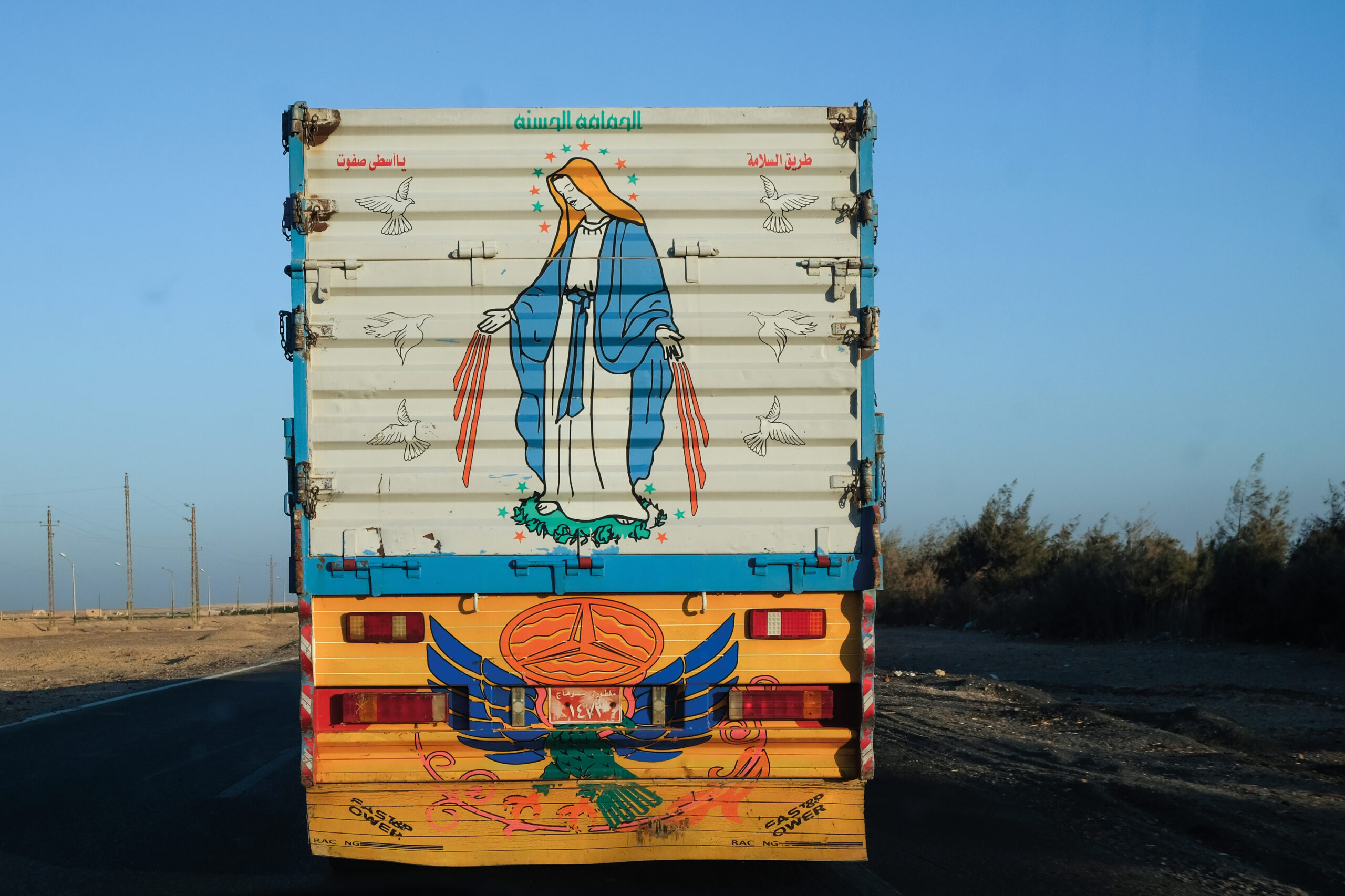 a truck on the road with word inscription and coptic illustrations on the back 