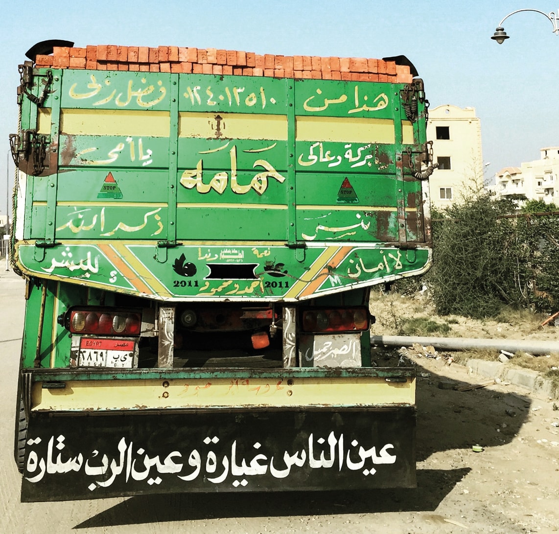 a truck on the road with word inscription and drawings on the back 